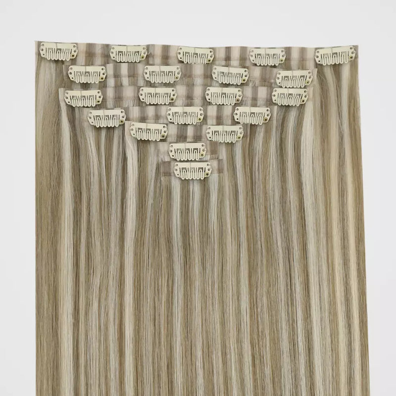 Load image into Gallery viewer, A bundle of hair extension clip ins on a plain light gray background. The extensions have a warm light brown and beige ombre pattern with multiple individual hair strands attached to beige metal clip tabs.