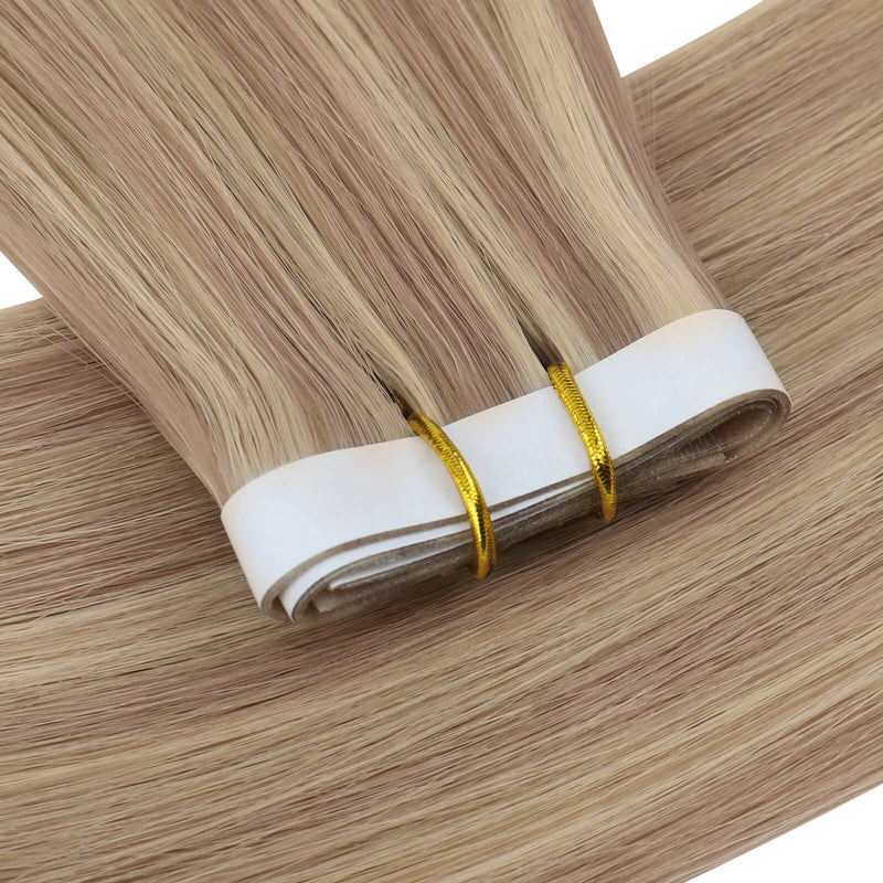 Load image into Gallery viewer, One bundle of straight invisible tape-in weft hair extensions featuring pink blonde highlights, secured with white bands and gold elastic ties, displayed on a white background.