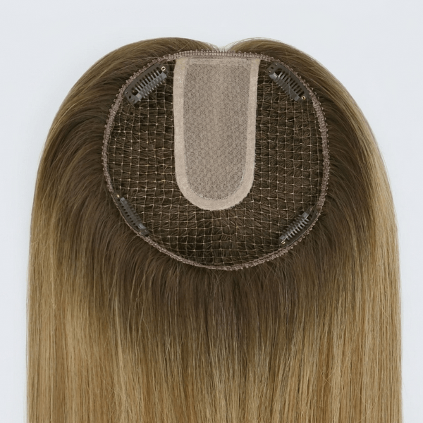 Brown hairpiece with a mesh base on a white background