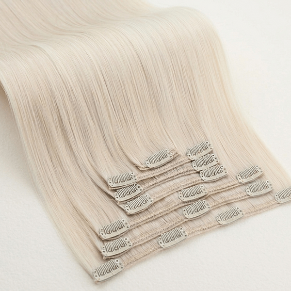 Set of blonde clip hair extensions on a light background