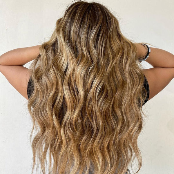 Woman with long, wavy, blonde hair against a neutral background