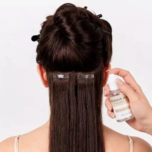 Person with hair extensions holding a bottle of adhesive on a white background