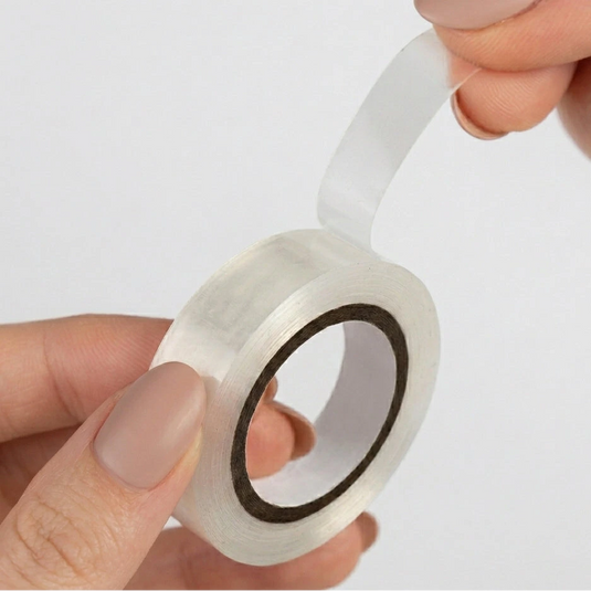 Clear tape roll held by a hand on a light gray background