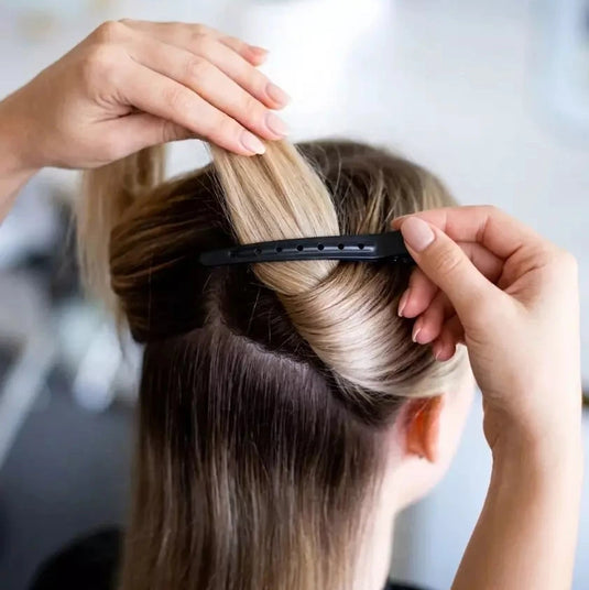 Person styling hair with a hair extension in a salon setting