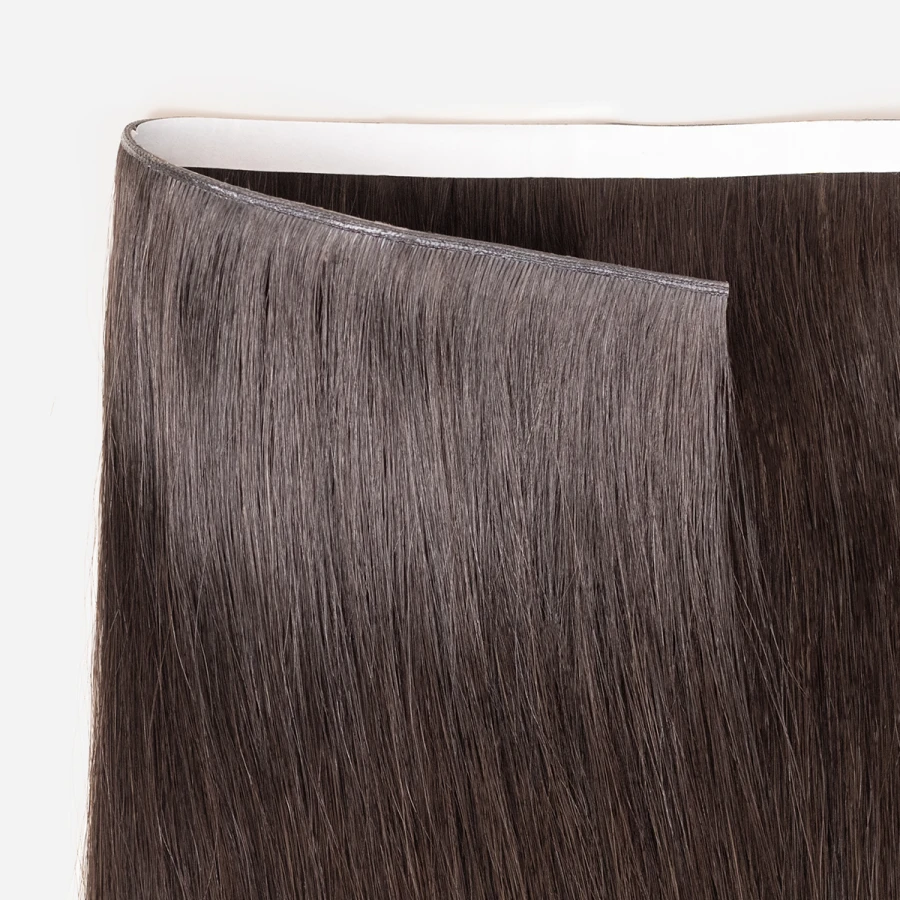 Close-up of brown tape in weft hair extensions on a white background