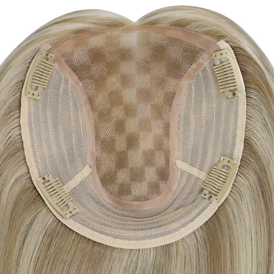 A close-up of a straight hairpiece section, showing the beige adhesive base and dark mesh with clip-in springs, on a plain white background.
