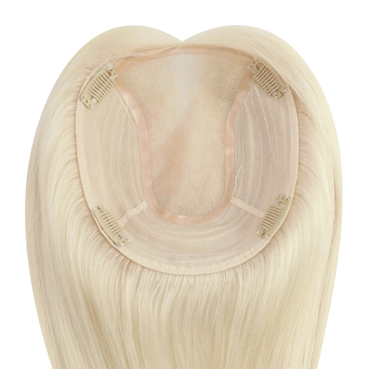 A close-up of a straight hairpiece section, showing the beige adhesive base and beige mesh with clip-in springs, on a plain white background