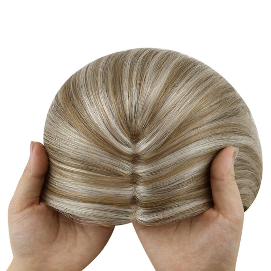 A close-up of a topper section with straight, glossy strands in a blended light brown and blonde balayage pattern, isolated on a white background.