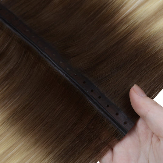 Close-up of a butterfly hair extension with a hand holding it, showing the texture and color gradient.
