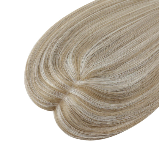 A close-up of a hair topper section with straight, smooth strands in a light ash blonde color, on a plain white background.