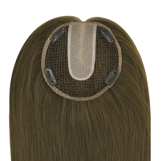 A close-up of a brown hairpiece extension showing the underside with a beige mesh center and four black clip-in clips, set against a plain white background.