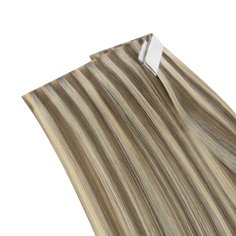 Load image into Gallery viewer, One bundle of straight invisible tape-in weft hair extensions featuring blonde highlights, secured with white bands and gold elastic ties, displayed on a white background.
