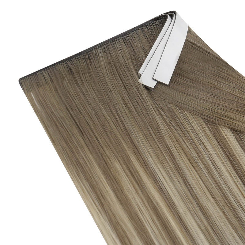 Load image into Gallery viewer, Three bundles of straight invisible tape-in weft hair extensions with blonde highlights on a white background.
