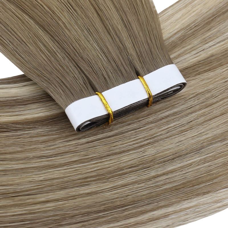 Load image into Gallery viewer, One bundle of straight invisible tape-in weft hair extensions featuring blonde highlights, secured with white bands and gold elastic ties, displayed on a white background.
