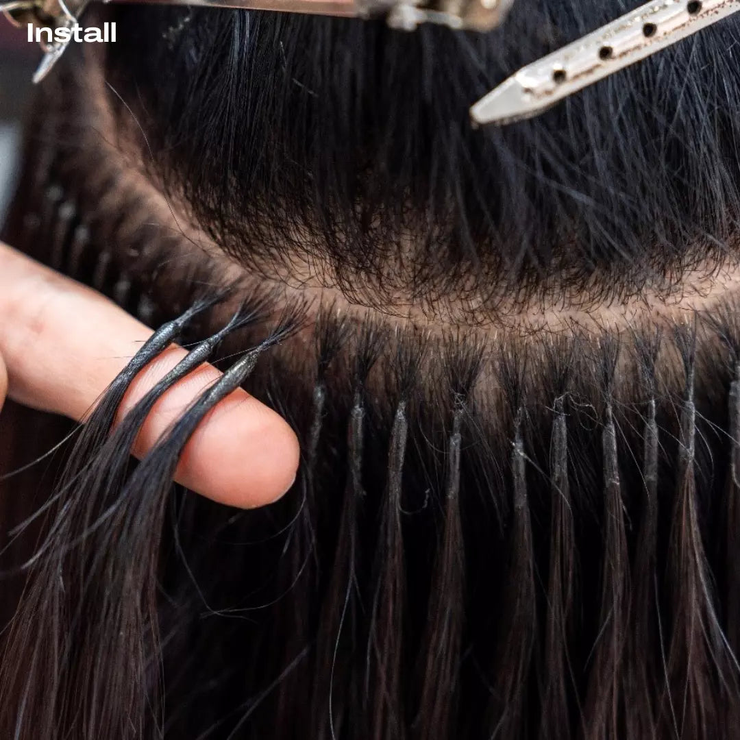 Close-up of keratin tip hair extensions being installed with a hand holding the hair.