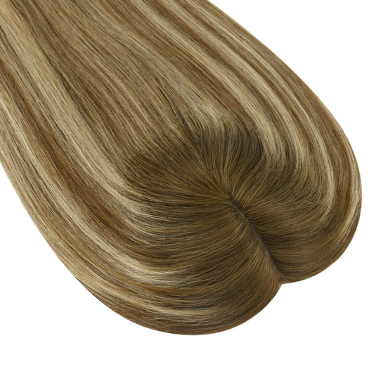 A close-up of a topper section with straight, glossy strands in a blended light brown and blonde balayage pattern, isolated on a white background.