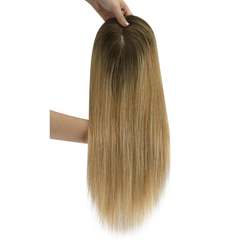 Load image into Gallery viewer, A long hairtopper with a warm golden-brown and light blonde ombré color, held up by a hand against a plain white background.
