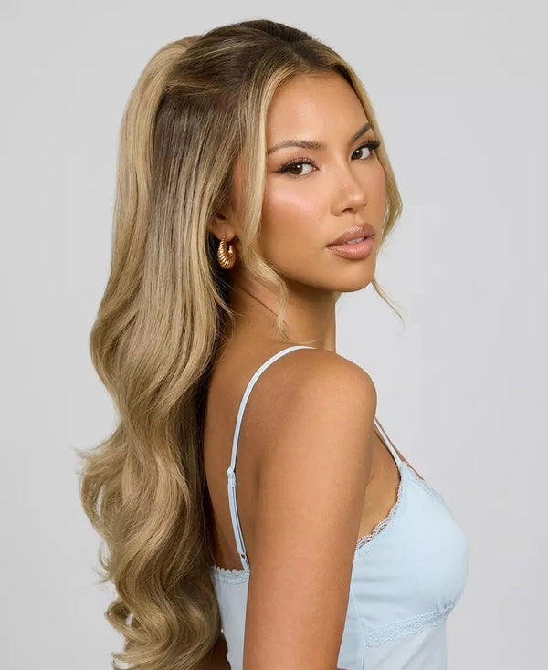 Woman with long, wavy hair wearing a light blue top against a plain background