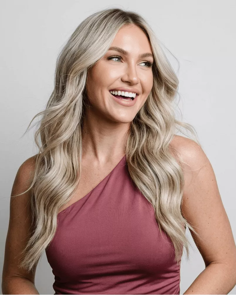 Woman wearing long platinum blonde hair extensions with silky texture and elegant volume.