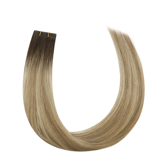 Blonde hair extensions with a brown root on a white background
