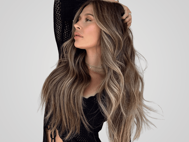 Woman with long, wavy hair posing against a plain background