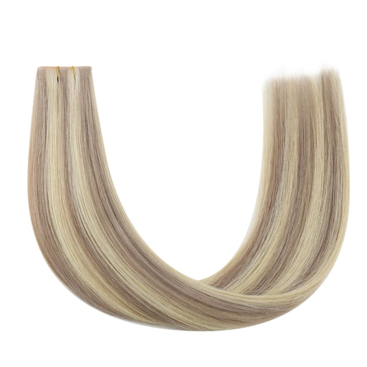 A close-up of a human hair butterfly weft hair extension bundle with long, straight strands in alternating light beige and medium brown tones.