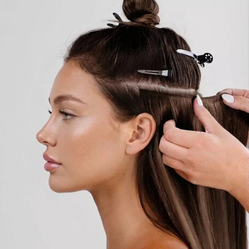 Woman with hair styled in a bun and clip, with another hand adjusting the hair.