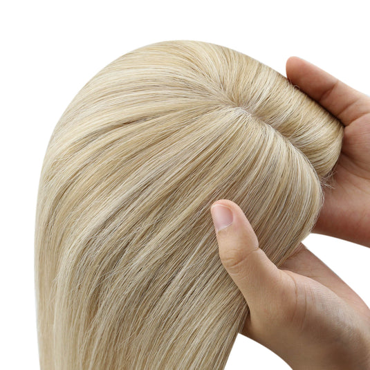 A close-up of a hair topper section with straight, smooth strands in a light ash blonde color, on a plain white background.