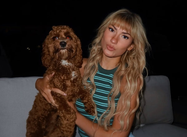 Woman holding a brown dog on a dark background