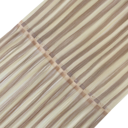 A close-up of a human hair butterfly weft hair extension bundle with long, straight strands in alternating light beige and medium brown tones.