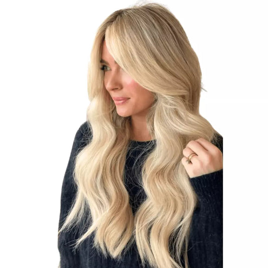 Woman with long wavy hair wearing an blonde topper on a white background