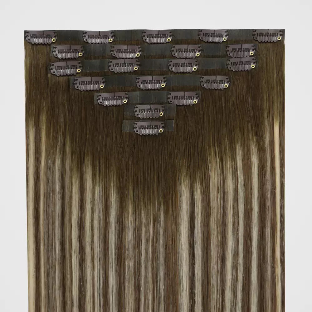 A close-up of blonde highlights clip in hair extensions on a white background