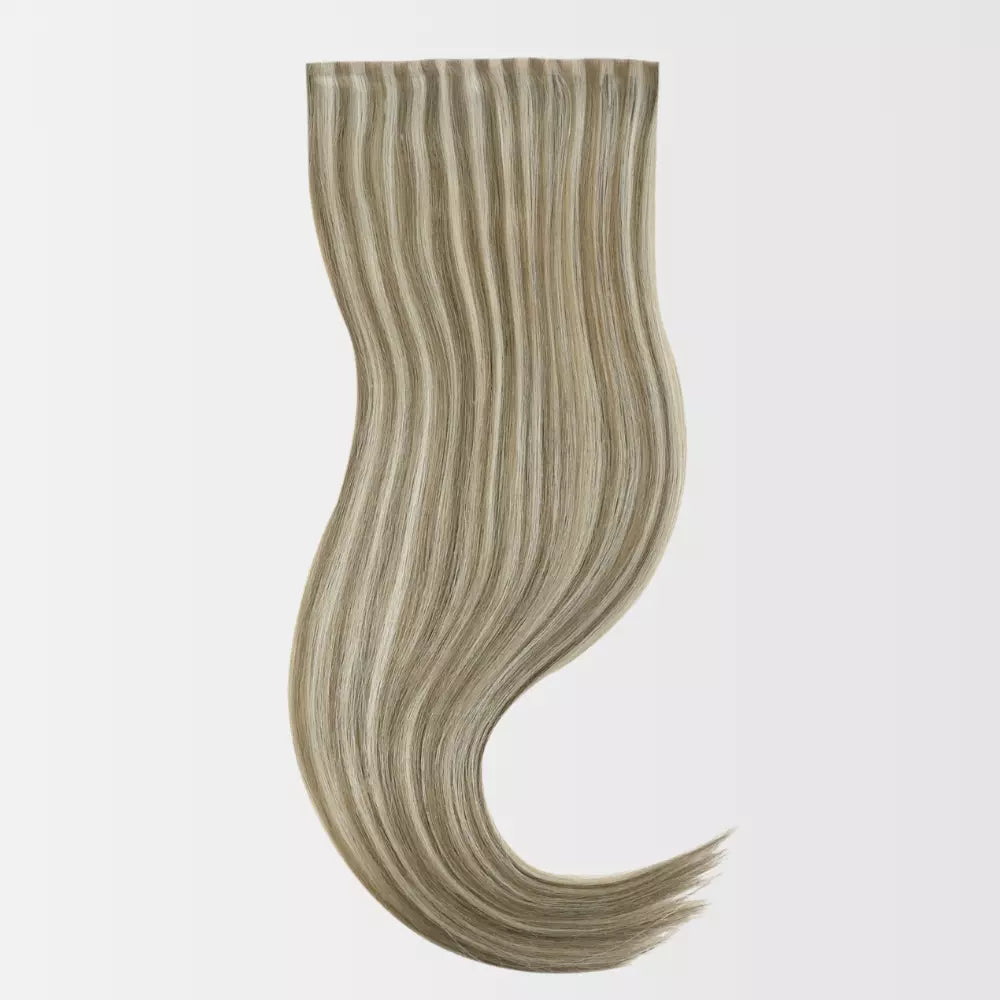 A wavy hair extension clip-in piece with blended light brown and blonde highlights, shown against a plain light gray background.