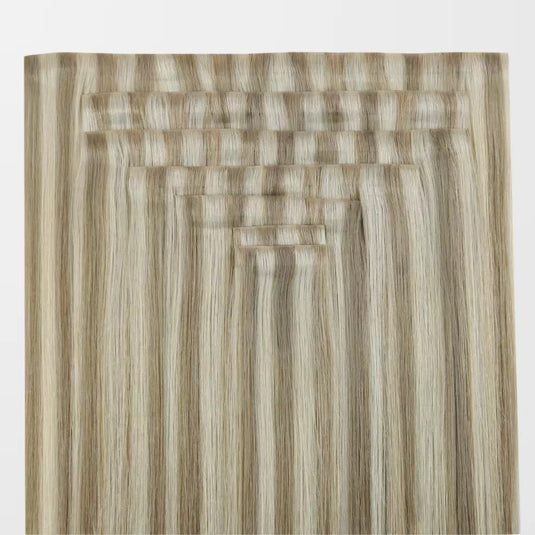 A close-up of blonde highlights clip in hair extensions on a white background