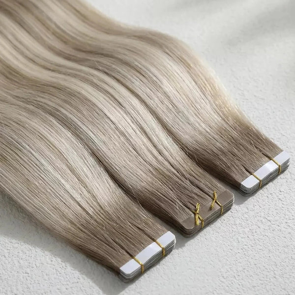 Set of blonde tape in hair extensions on a light gray background