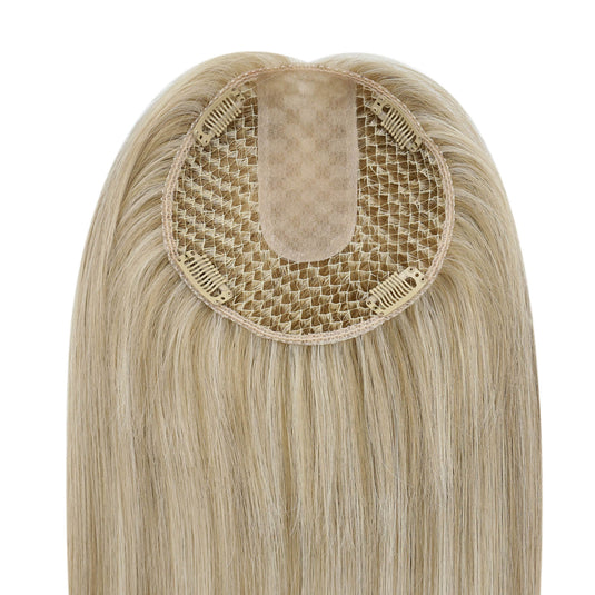 A close-up of a hairpiece with long straight light blonde hair and a beige mesh attachment center, shown against a plain white background.