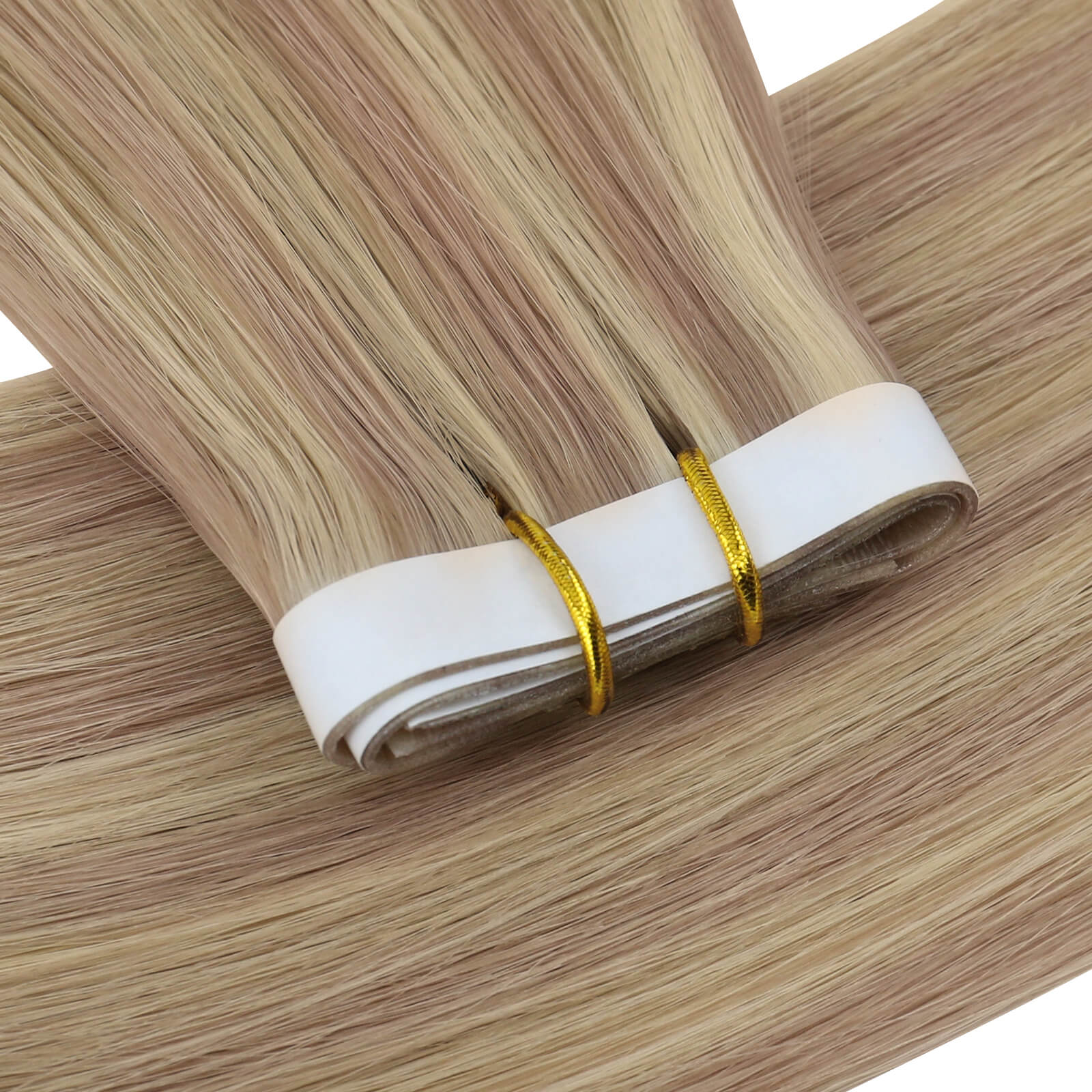 One bundle of straight invisible tape-in weft hair extensions featuring pink blonde highlights, secured with white bands and gold elastic ties, displayed on a white background.