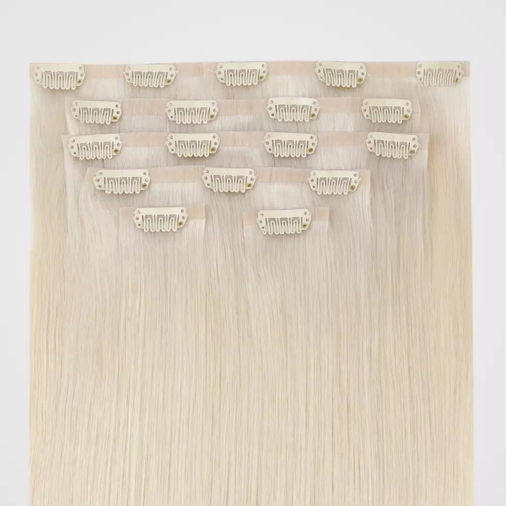 Set of blonde invisible hair extensions with clips on a white background