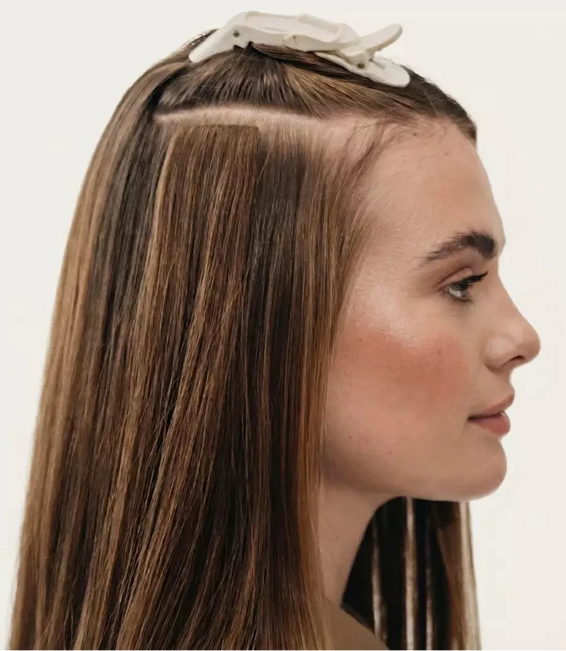 Woman with long brown hair wearing a white headband on a light gray background